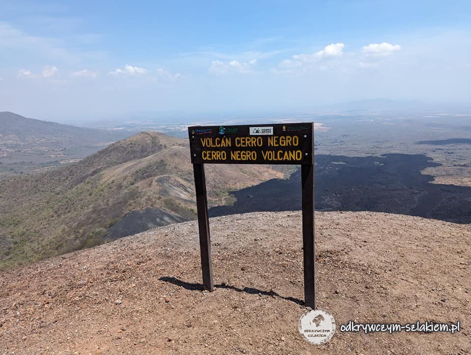 Tablica Volcán Cerro Negro na szczycie wulkanu, w tle równina wokół León