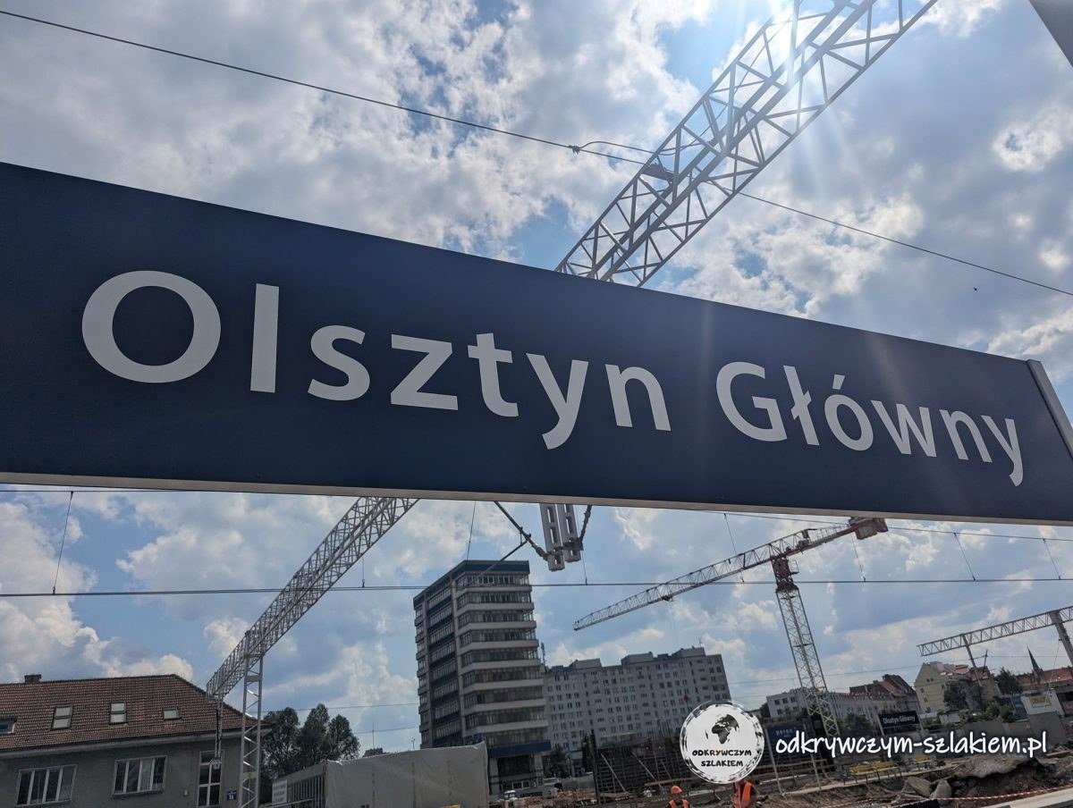 The Olsztyn Główny sign on the platform, with construction cranes behind, June 2023