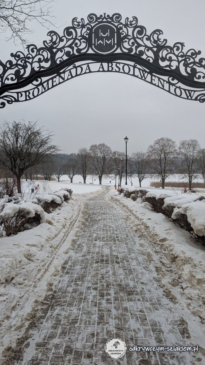 The gate with the inscription Promenada Absolwentów (Graduates' Promenade) on the Kortowo campus in winter