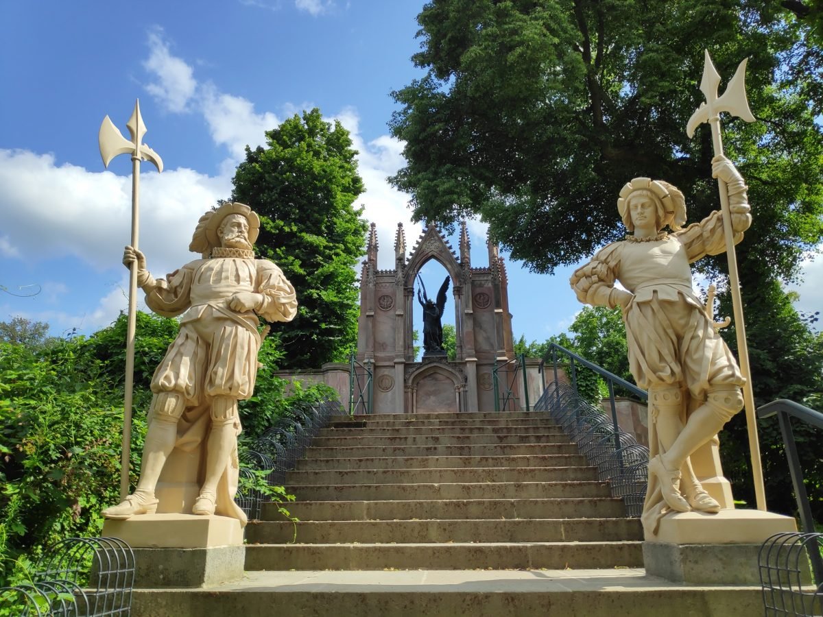 Schody z posągami halabardników prowadzące do neogotyckiego pomnika z figurą anioła w parku Babelsberg