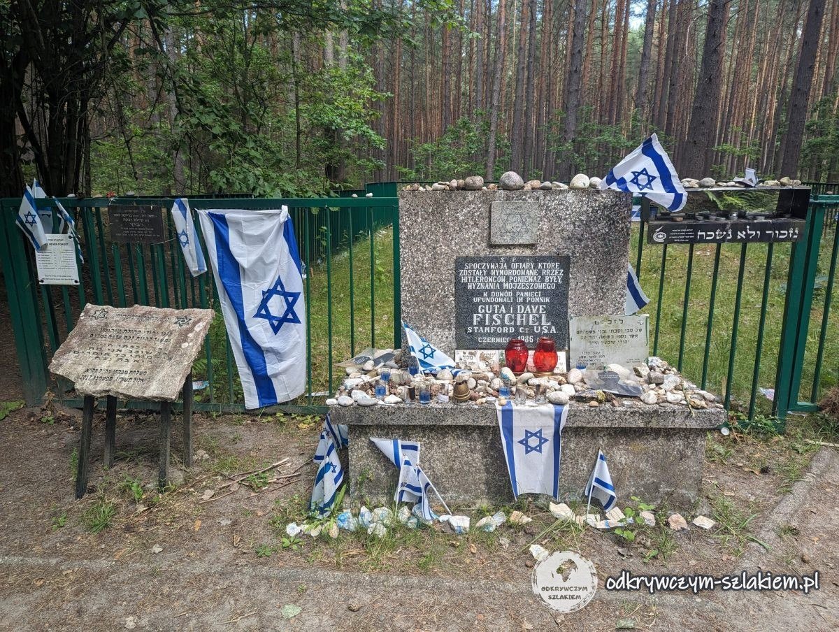 Gedenktafel mit Grablichtern, Steinchen und israelischen Fahnen im Wald von Łopuchowo