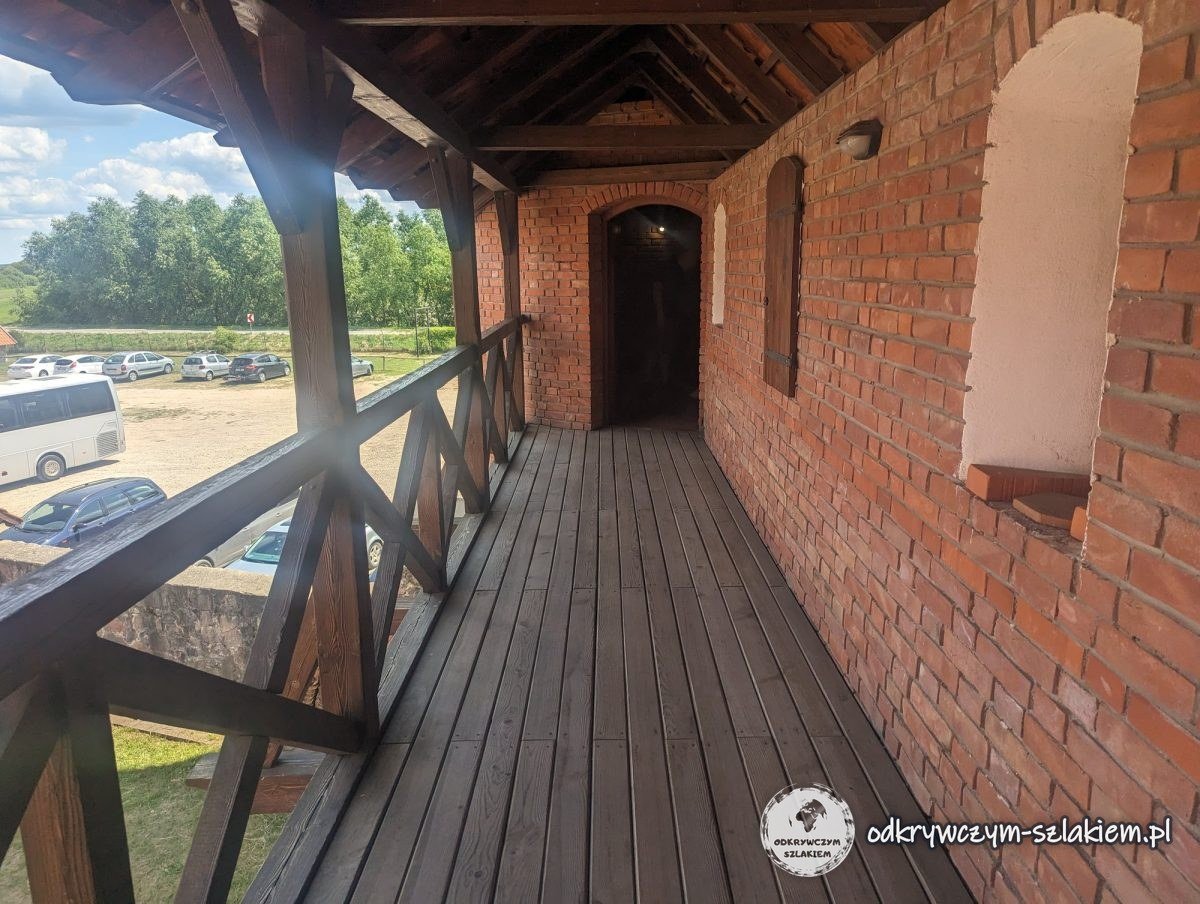 Überdachter Holzgang an den Backsteinmauern der Burg Tykocin