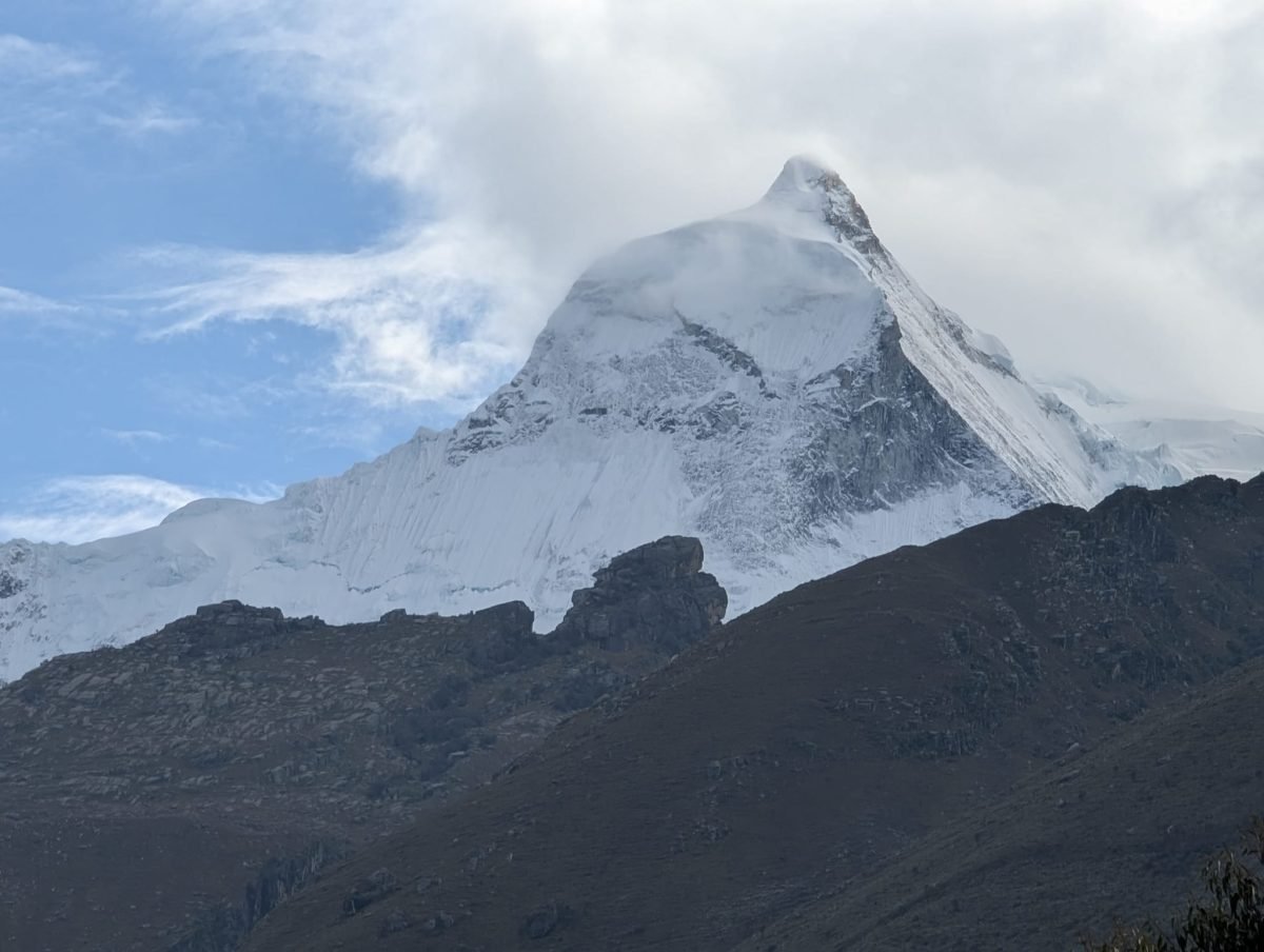 Ośnieżony, ostry szczyt Cordillera Blanca o świcie nad ciemnymi zboczami doliny