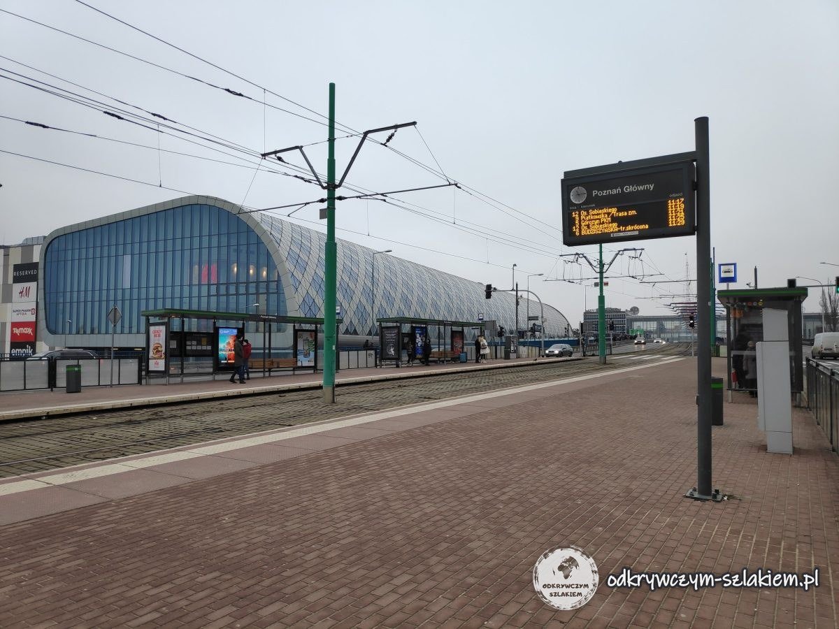 A tram stop by the modern building of Poznań Główny station