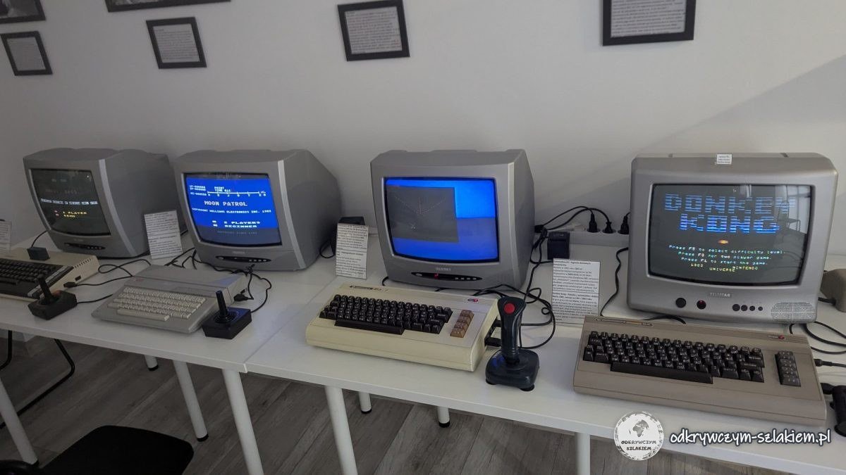 A row of 8-bit computers with joysticks and TVs, with Donkey Kong on one of the screens