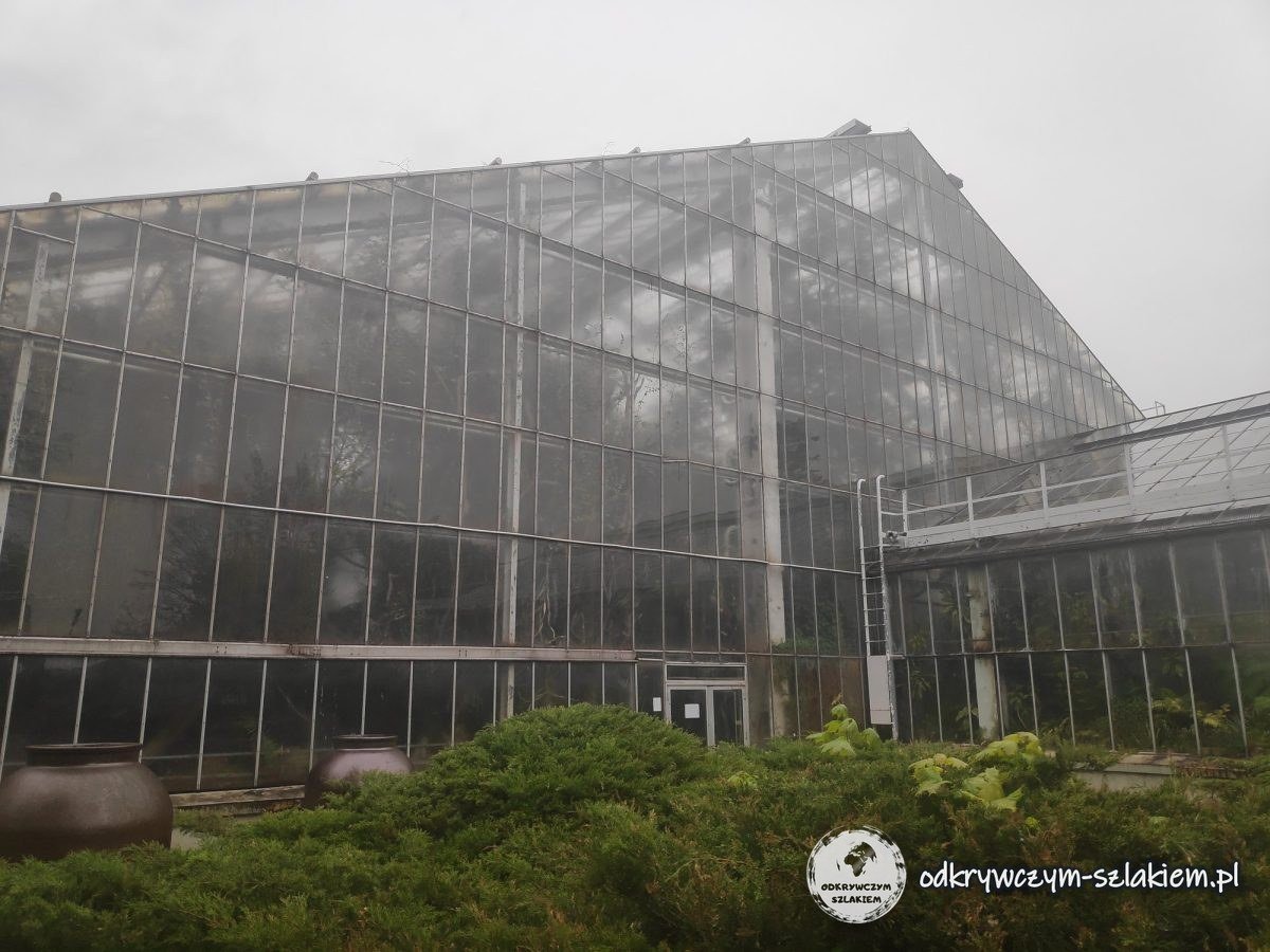 A glass pavilion of the Poznań Palm House in Wilson Park on a cloudy day