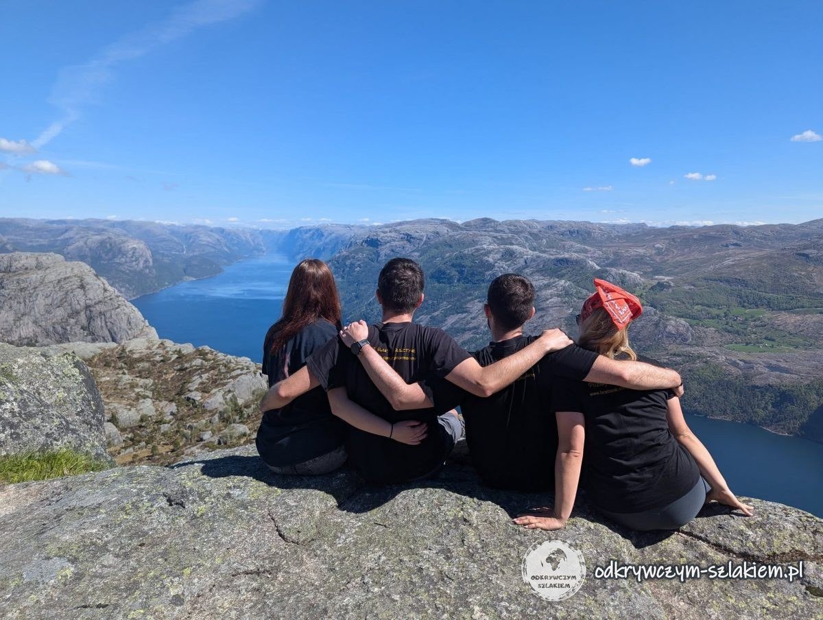 Cuatro personas sentadas en el borde del acantilado de Preikestolen sobre el Lysefjord