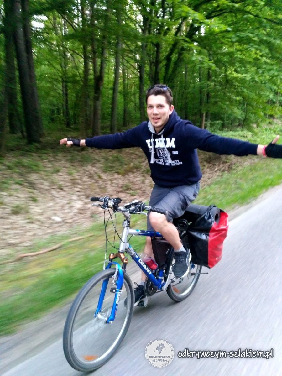 Rowerzysta jedzie z rozłożonymi rękami przez las w drodze do Olsztyna