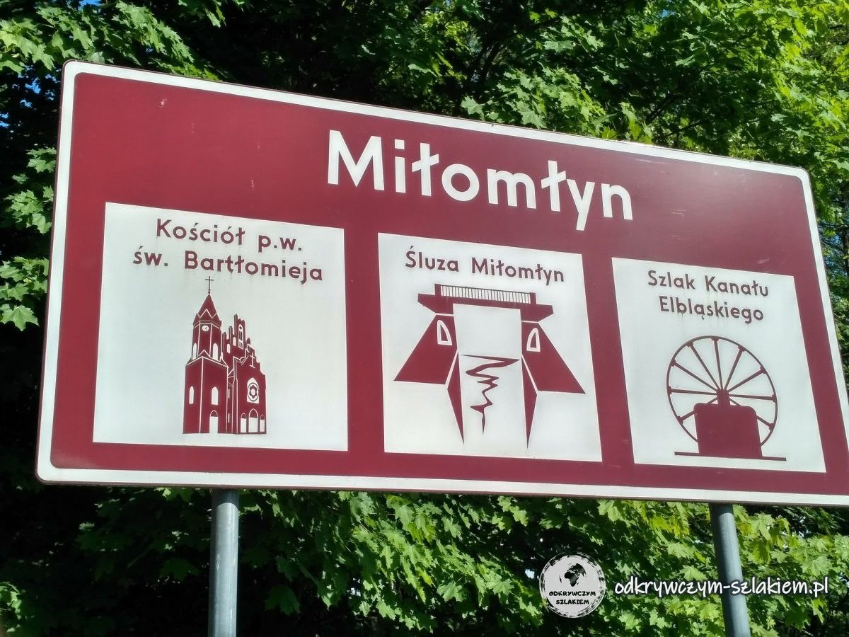 Brązowa tablica turystyczna Miłomłyna z kościołem św. Bartłomieja, śluzą i szlakiem Kanału Elbląskiego
