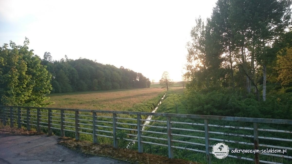 Polna droga wzdłuż metalowej barierki i pola o zachodzie słońca w okolicy Starego Dzierzgonia