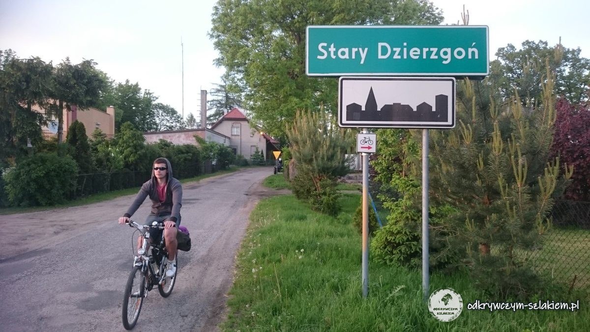 Michał na rowerze przy tablicy z nazwą wsi Stary Dzierzgoń