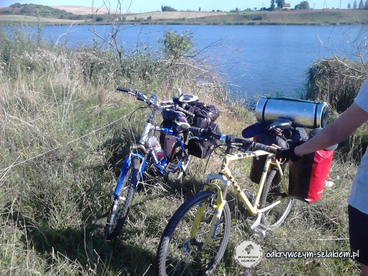 Zwei Fahrräder mit Packtaschen und Isomatte im hohen Gras am See