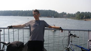 Postój z rowerami obładowanymi sakwami na moście w Mikołajkach, w tle jezioro z łodziami
