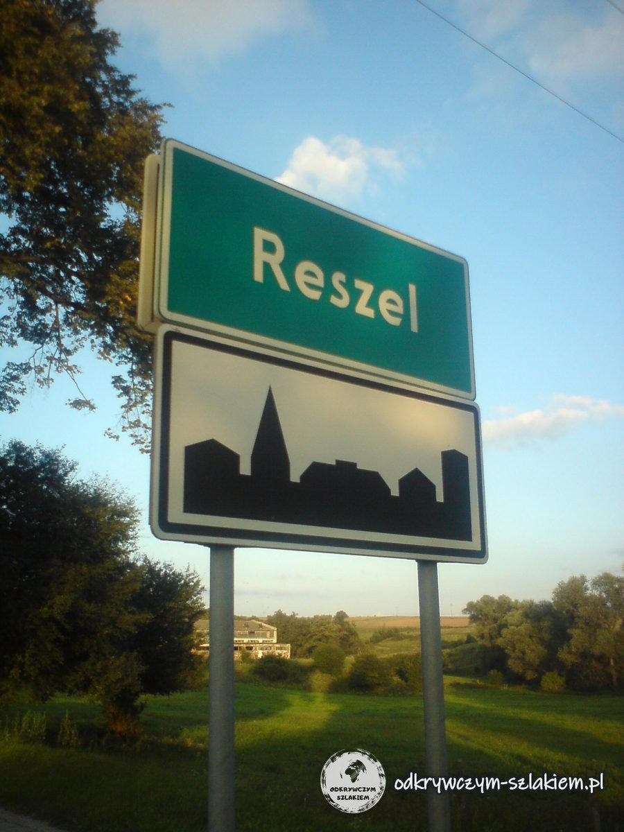 Das Ortsschild von Rößel (Reszel) an der Straße im Abendlicht