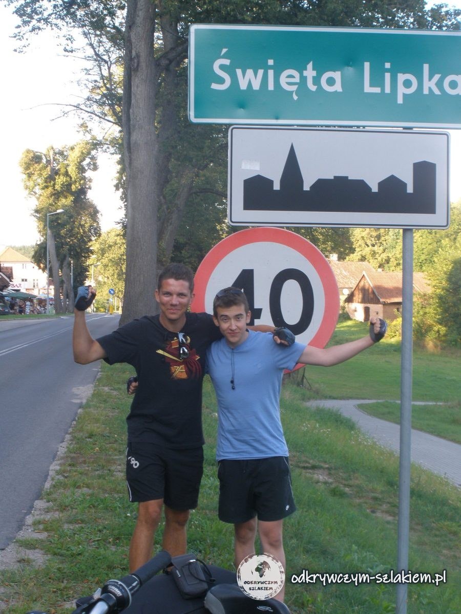 Zwei Radfahrer am Ortsschild von Heiligelinde und einem Tempo-40-Schild