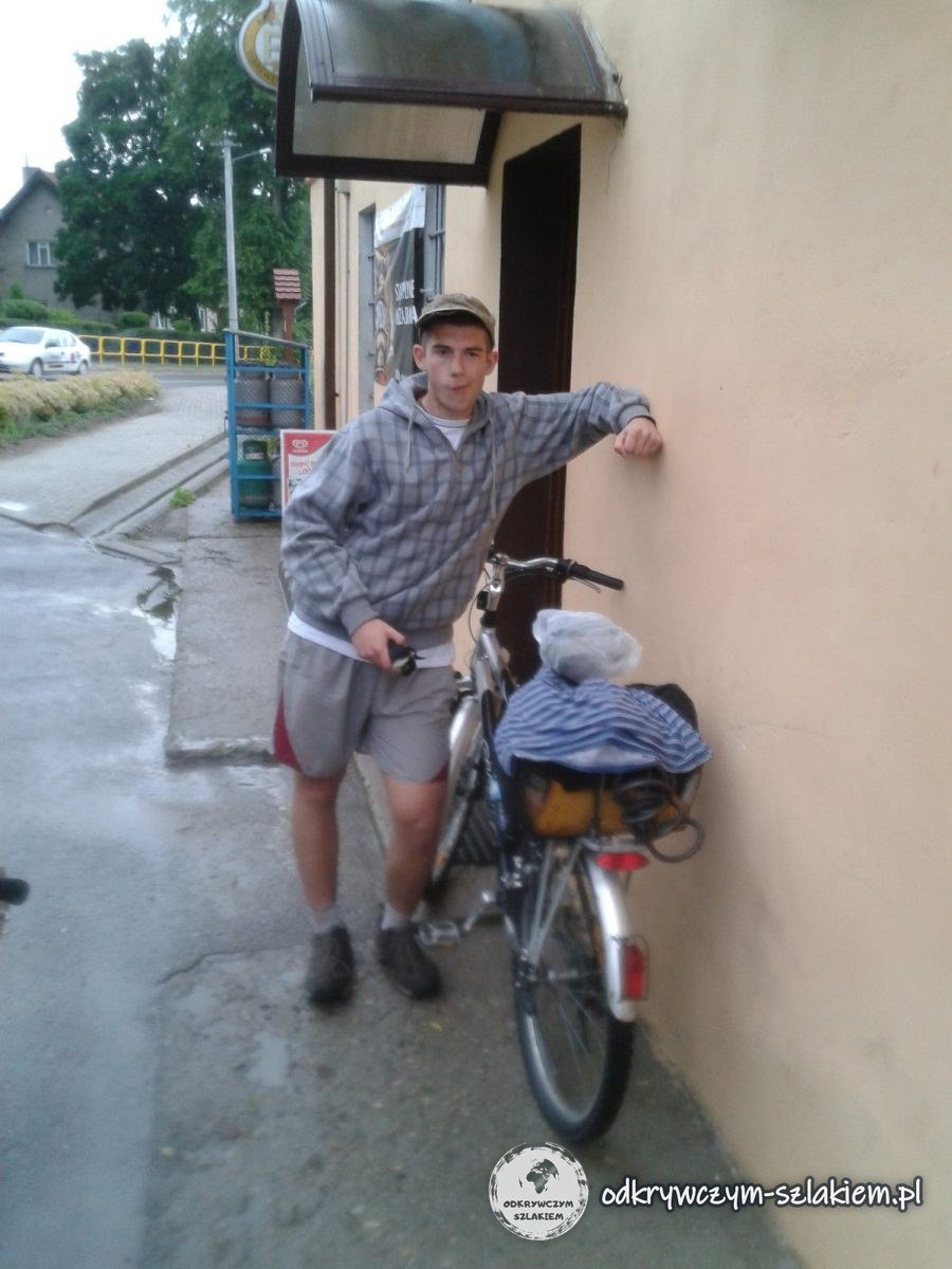 Michał mit Rad an der Wand des Dorfladens in Mostkowo