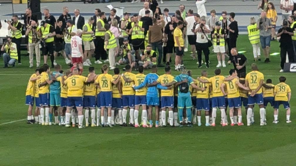 Piłkarze Brazylii w żółtych koszulkach w kręgu przed Meczem Legend, wokół fotoreporterzy