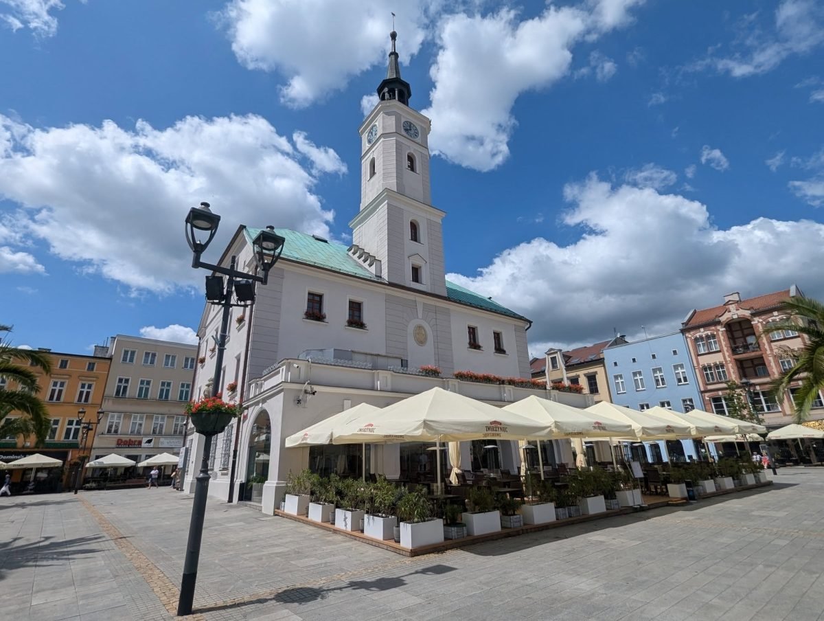 Ratusz z białą wieżą na środku rynku w Gliwicach i ogródki kawiarni z parasolami