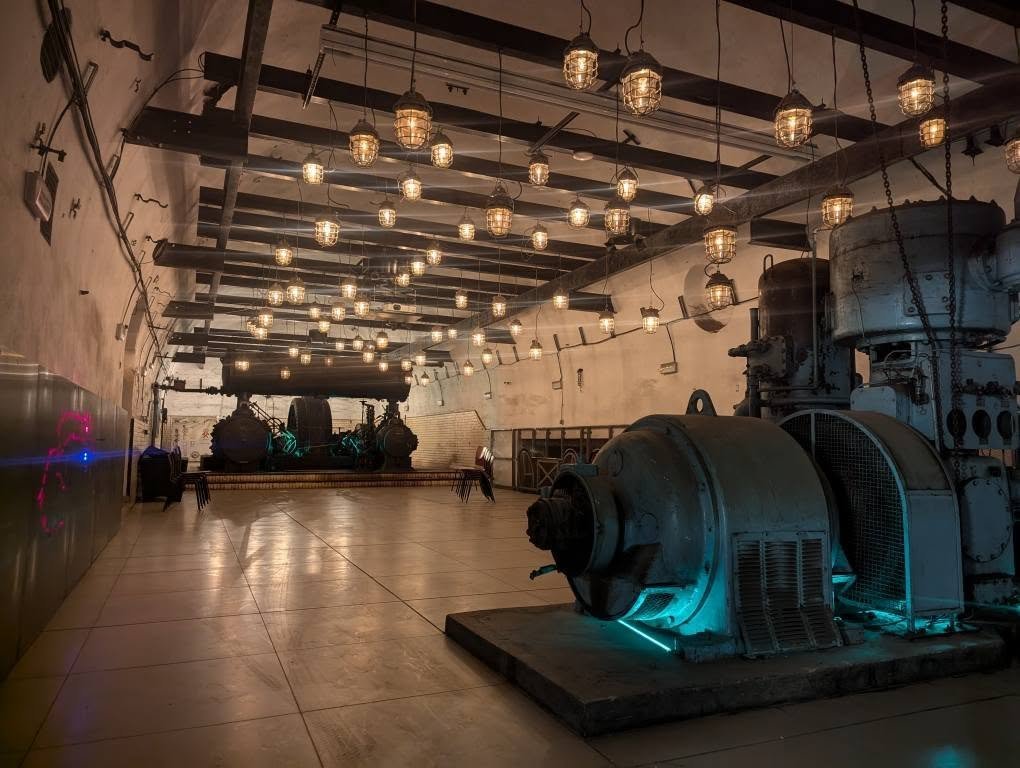 Sala z dawnymi maszynami i dziesiątkami lamp pod sufitem w kopalni Guido