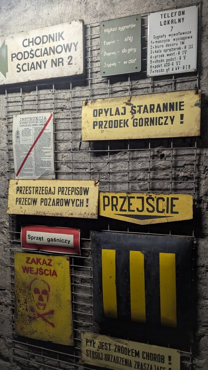 Górnicze tablice ostrzegawcze i drogowskazy na ścianie chodnika w kopalni Guido