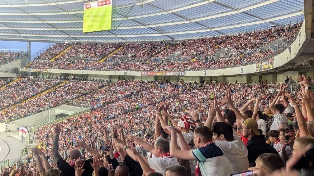 Kibice z rękami w górze na trybunie Stadionu Śląskiego