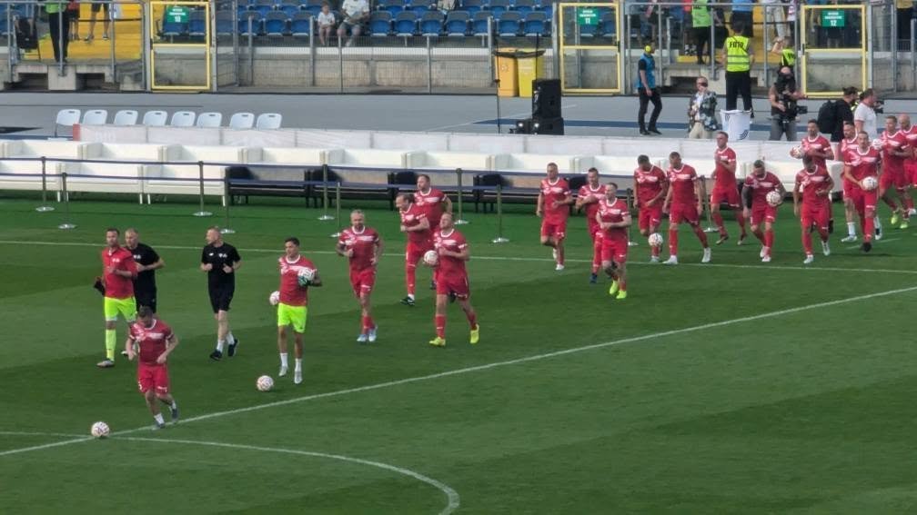 Polscy piłkarze w czerwonych strojach rozgrzewają się przed Meczem Legend na Stadionie Śląskim