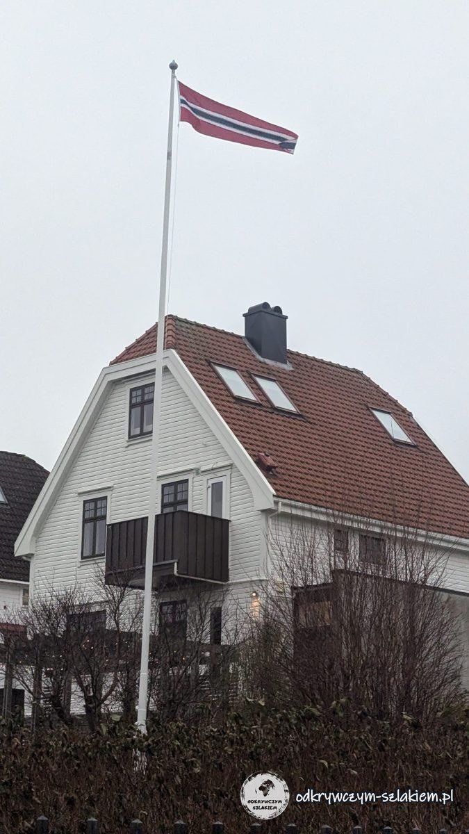 Biały drewniany dom z norweską flagą na maszcie w Stavanger