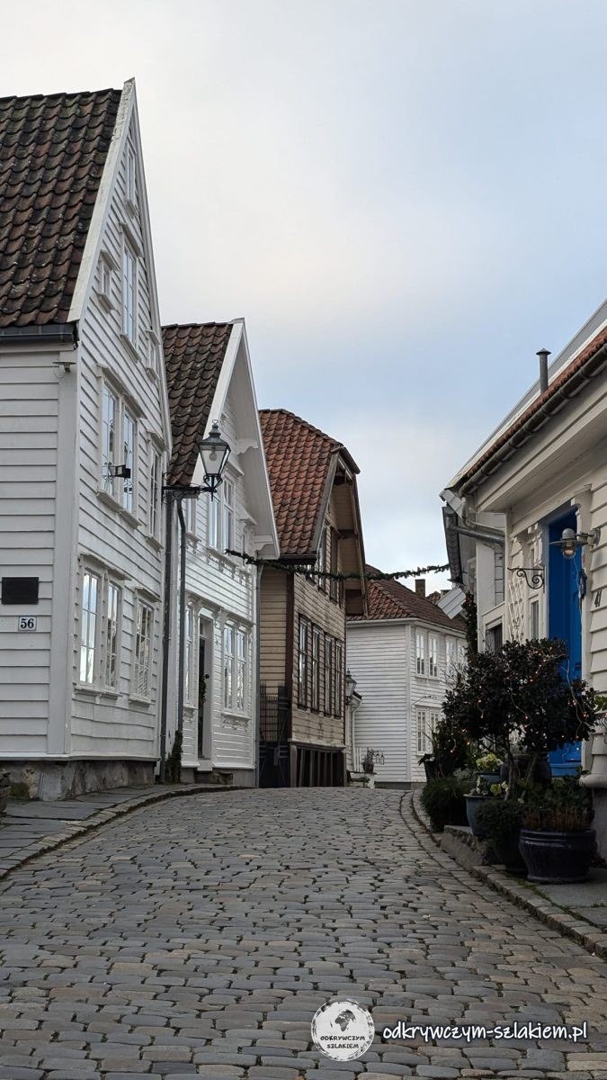 Wąska brukowana uliczka między białymi drewnianymi domami w Gamle Stavanger