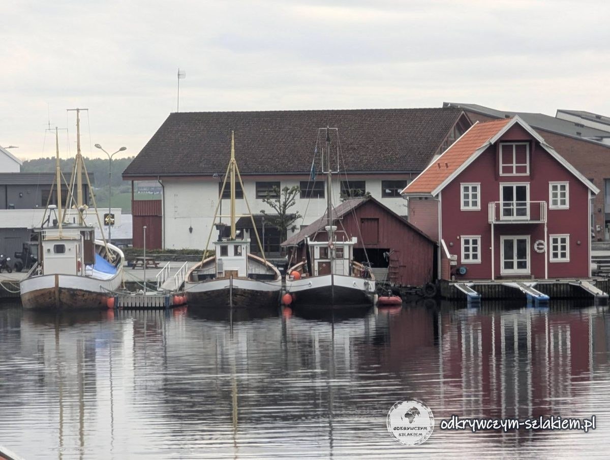 Drewniane łodzie i czerwony dom w małym porcie na wyspie Rennesøy