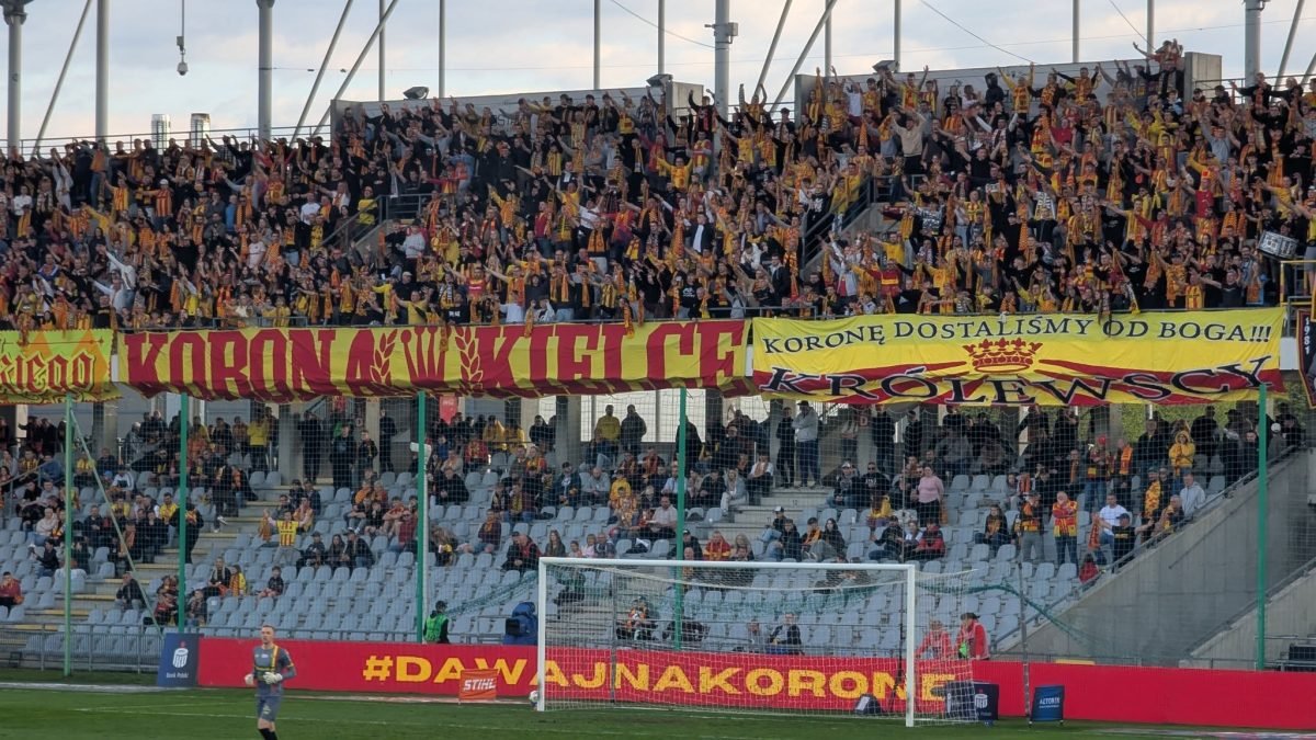 Kibice Korony Kielce z żółto-czerwonym transparentem na trybunie stadionu w Kielcach