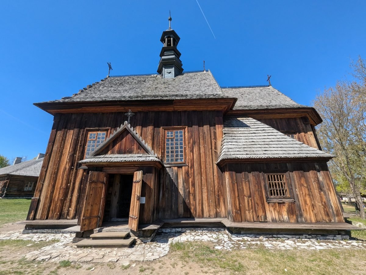 Drewniany kościół z gontowym dachem i sygnaturką w skansenie w Tokarni