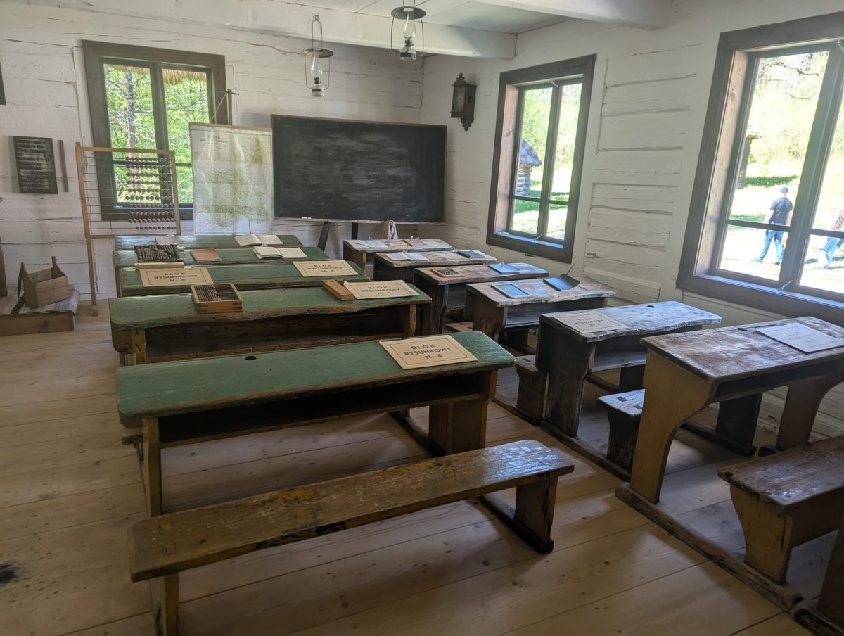 Dawna wiejska klasa z drewnianymi ławkami i tablicą w skansenie w Tokarni