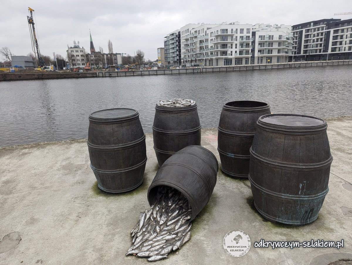 Escultura de los barriles de Szczecin en el bulevar: de un barril volcado salen arenques de metal