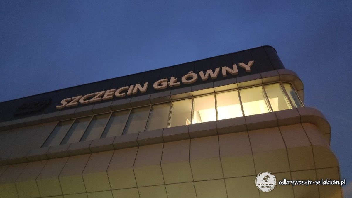 Letrero iluminado SZCZECIN GŁÓWNY en el edificio de la estación al anochecer