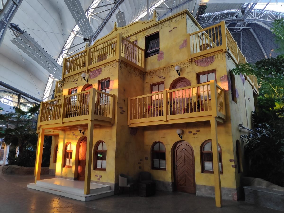 Żółty kolonialny dom z drewnianymi balkonami – Tropical Islands