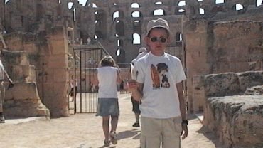 Na tle kamiennych arkad rzymskiego amfiteatru w El Jem