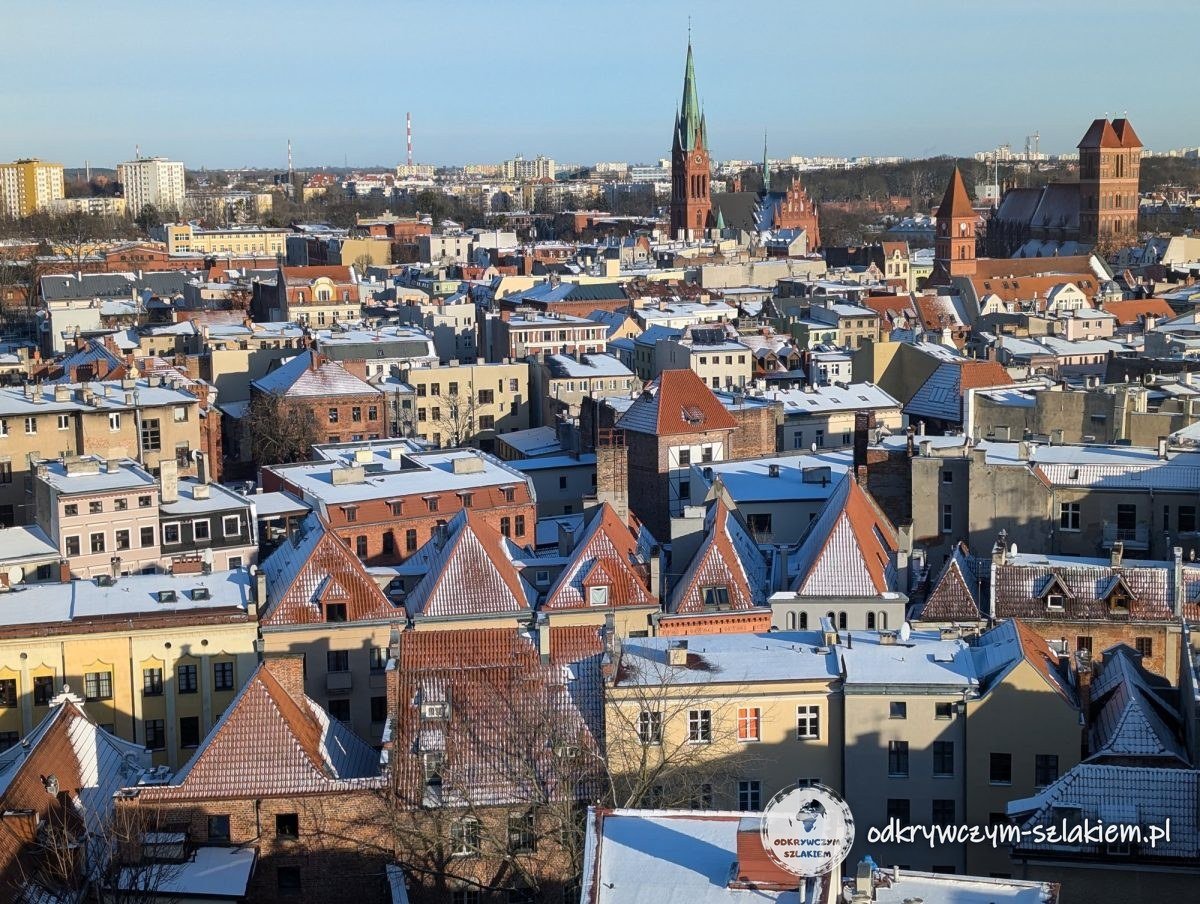 Tejados rojos de Toruń cubiertos de nieve y torres de iglesias vistos desde la torre del Ayuntamiento