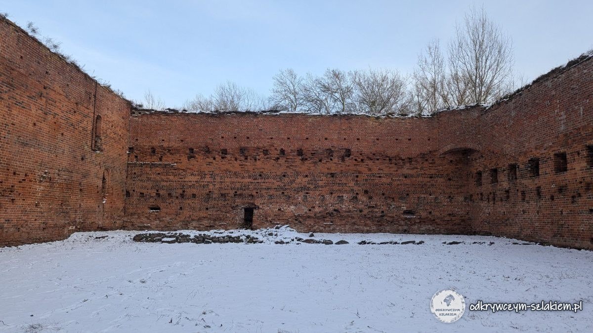 Ruinas del castillo de Dybów en Toruń: murallas de ladrillo y nieve en el patio