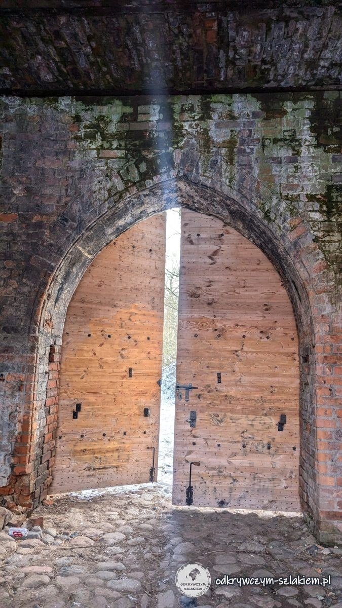 Paso en arco apuntado en la muralla de ladrillo del castillo de Dybów