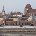 Panorámica del casco antiguo de Toruń desde la orilla izquierda del Vístula: la catedral de los Santos Juanes, el Ayuntamiento y las murallas reflejados en el agua en calma