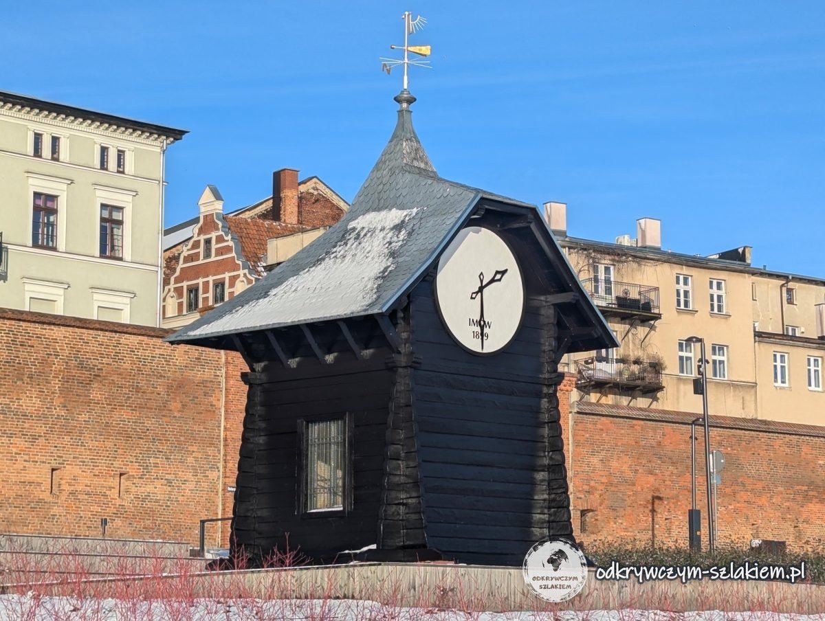 Caseta de madera con una esfera como de reloj que indica el nivel del agua, junto a las murallas del Vístula en Toruń