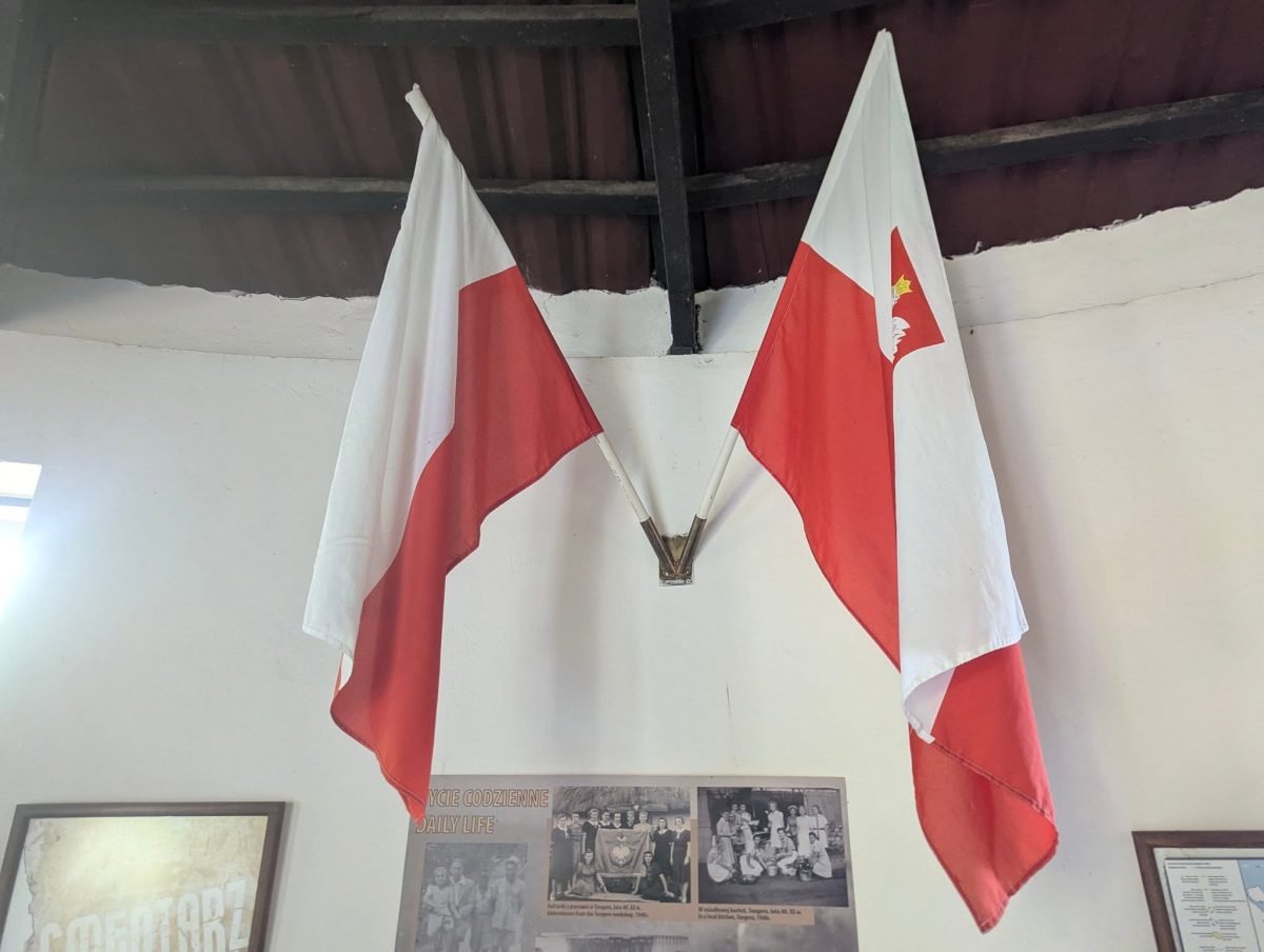 Polskie flagi i stare zdjęcia w budynku przy cmentarzu w Tengeru