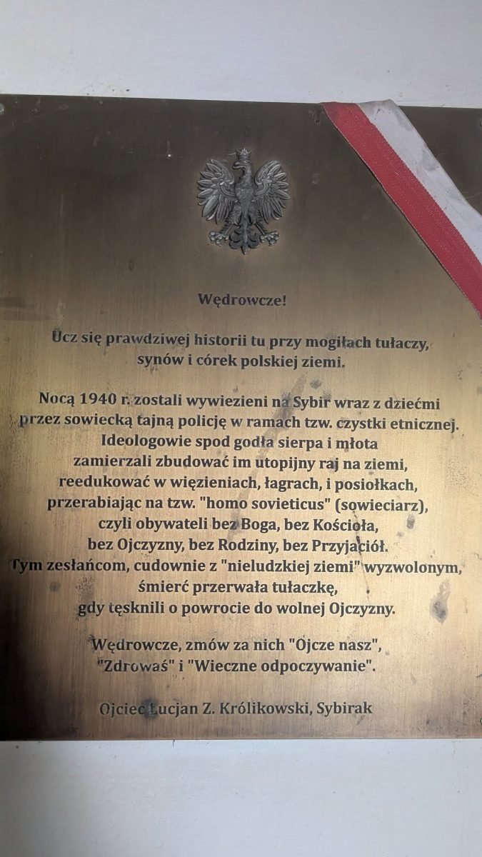 Tablica „Wędrowcze!” z orłem i biało-czerwoną wstęgą na cmentarzu w Tengeru