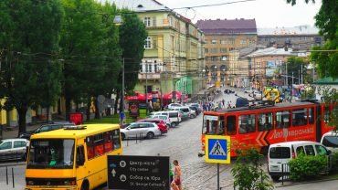 Tramwaj i żółta marszrutka na ulicy we Lwowie, w tle kamienice starego miasta