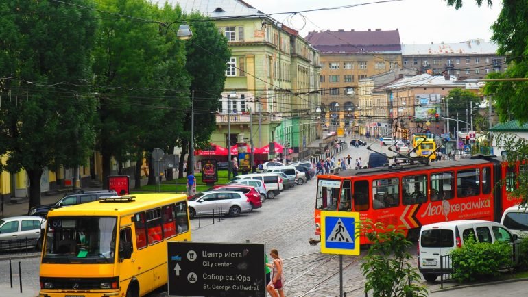 Tramwaj i żółta marszrutka na ulicy we Lwowie, w tle kamienice starego miasta