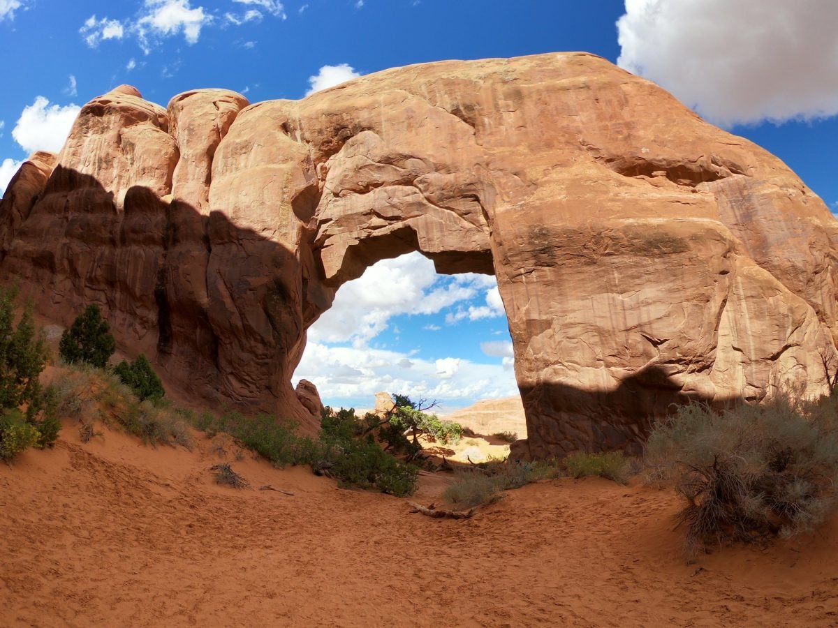 Łuk skalny nad piaszczystą ścieżką w Parku Narodowym Arches