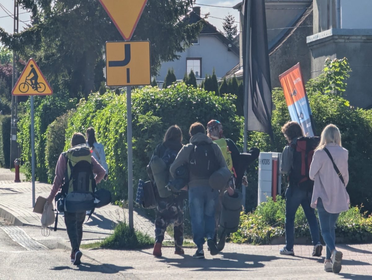 Uczestnicy z plecakami idą ulicą Olsztyna na początku trasy „Odkrywcy”