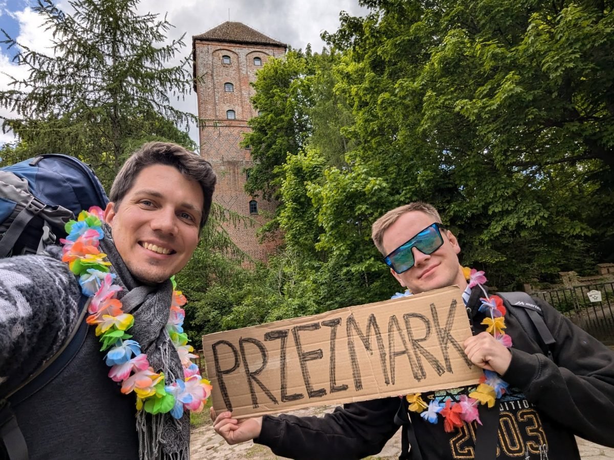 Maciek i Krzysiek z tabliczką „Przezmark” przy wieży ruin zamku w Przezmarku