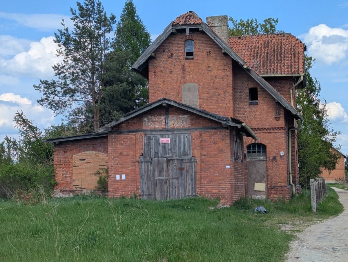 Stary ceglany budynek przy dawnej linii kolejowej na trasie z Kętrzyna