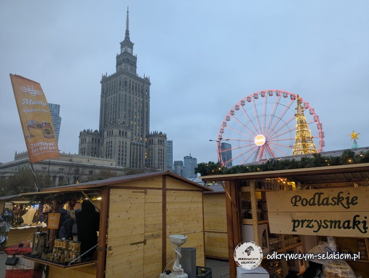 Casetas de madera del mercado navideño con una noria junto al Palacio de la Cultura y la Ciencia